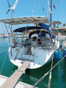 Ein Segelboot im Hafen, verbunden mit dem Steg über eine Rampe, mit Windgenerator und Solarpanel auf dem Deck.